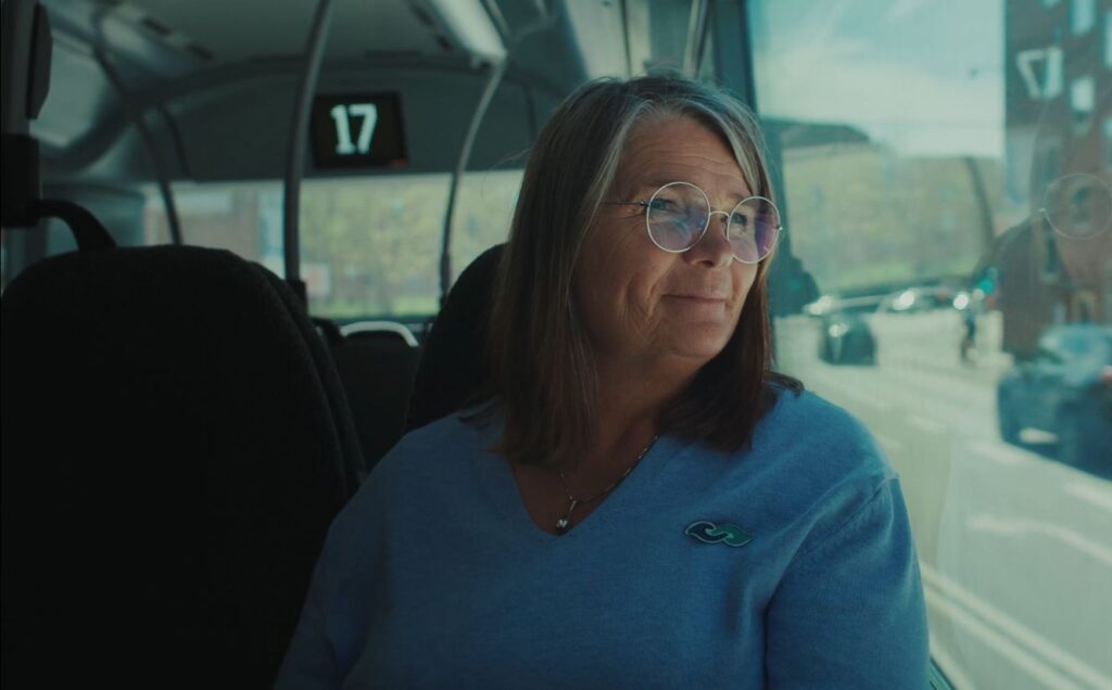 Kvinde sidder og kigger ud af vinduet i en bus