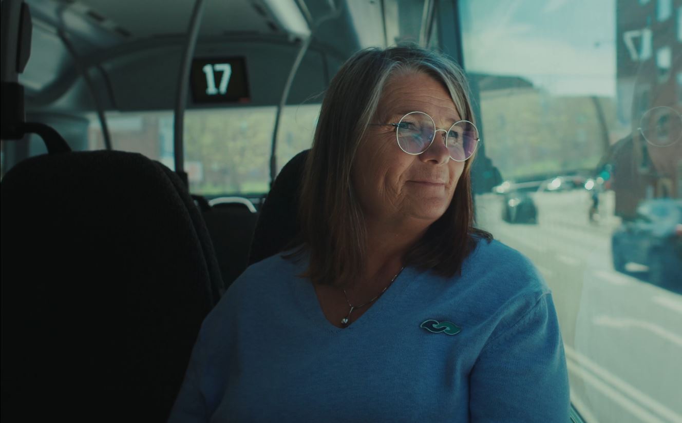 Kvinde sidder og kigger ud af vinduet i en bus
