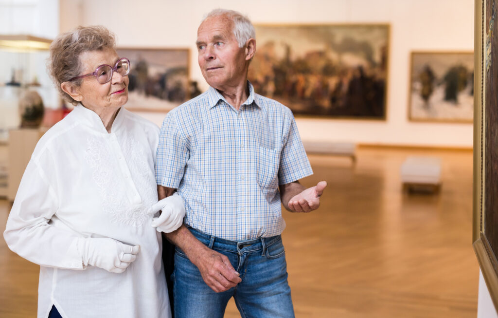 Ældre par ser på kunstværker i en udstilling.