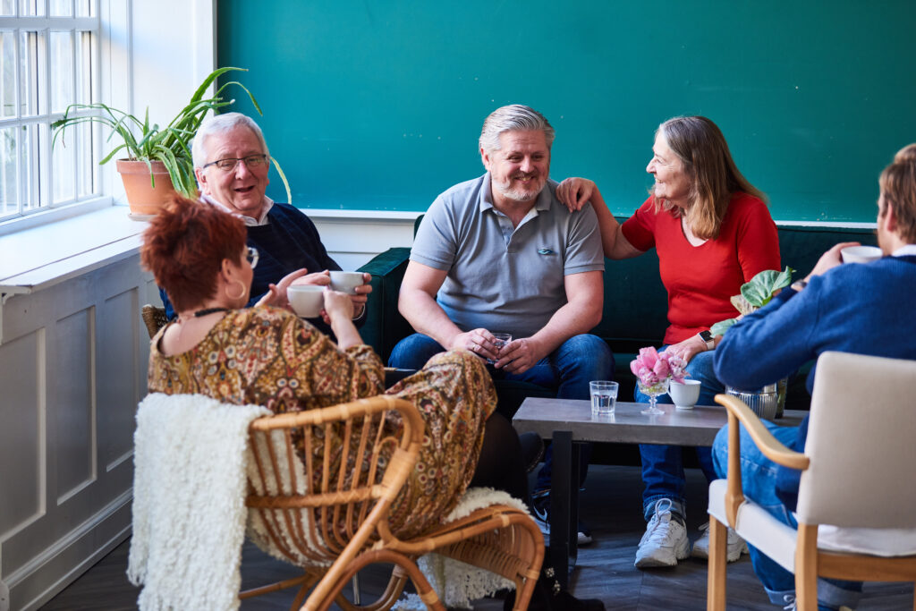 To kvinder med demenssymbolet taler sammen og smiler.