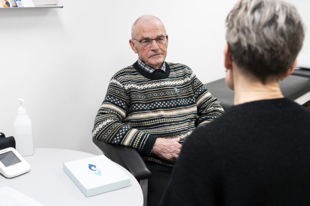 Mand med demens taler med sygeplejersken i lægeklinik