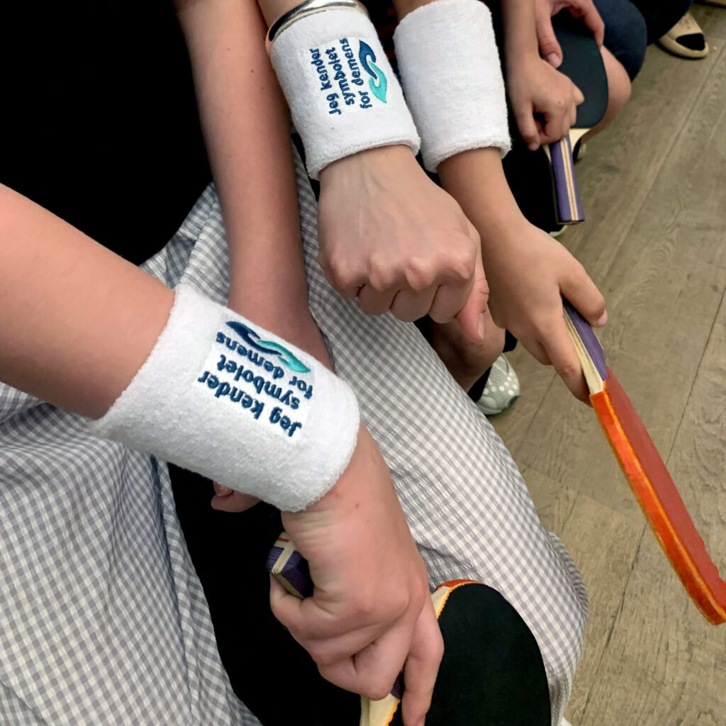 En gruppe deltagere med svedbånd og bordtennisbat under opvisningskampen i Absalon