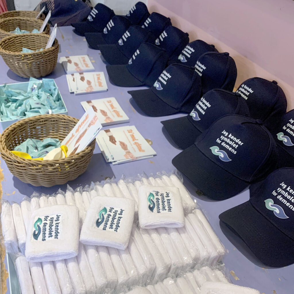 Hatte, svedbånd og andet merch med Demenssymbolet gjort klar til klar til Demensugen i Absalon